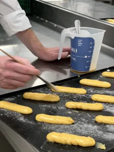 Uitgespoten souzendeeg voor eclairs afwerken met een laagje ei