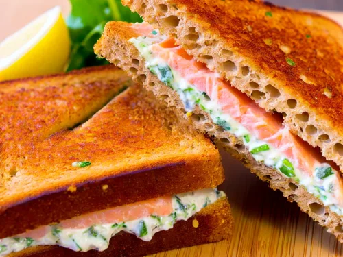 A Croque Norvégien sandwich, featuring two slices of toasted whole wheat bread. The sandwich is made with smoked salmon and herb cream cheese.