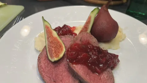 Hertengebraad op een bedje van knolselderpuree met gestoofd peer in rode wijn siroop met een veenbessencompote saus