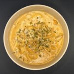 Bovenzicht van champignonroomsaus met witte wijn en room, afgewerkt met oregano